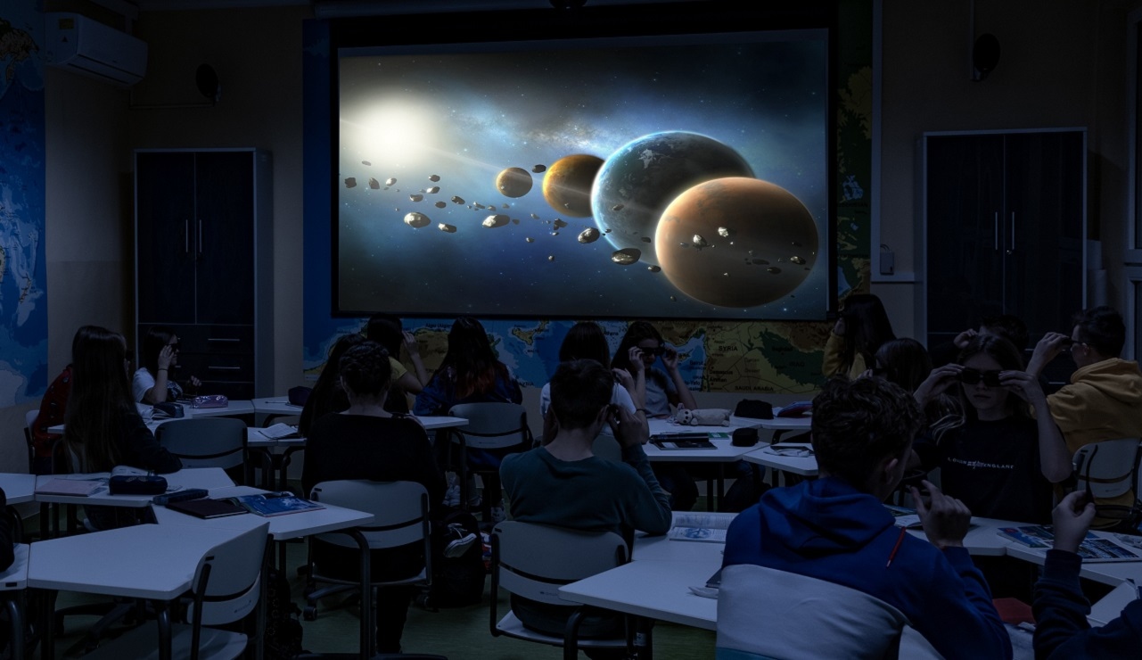 Zdjęcie przedstawiające uczniów w czasie zajęć geografii. Uczniowie w okularach do filmów 3d oglądają trójwymiarowy film o układzie słonecznym.
